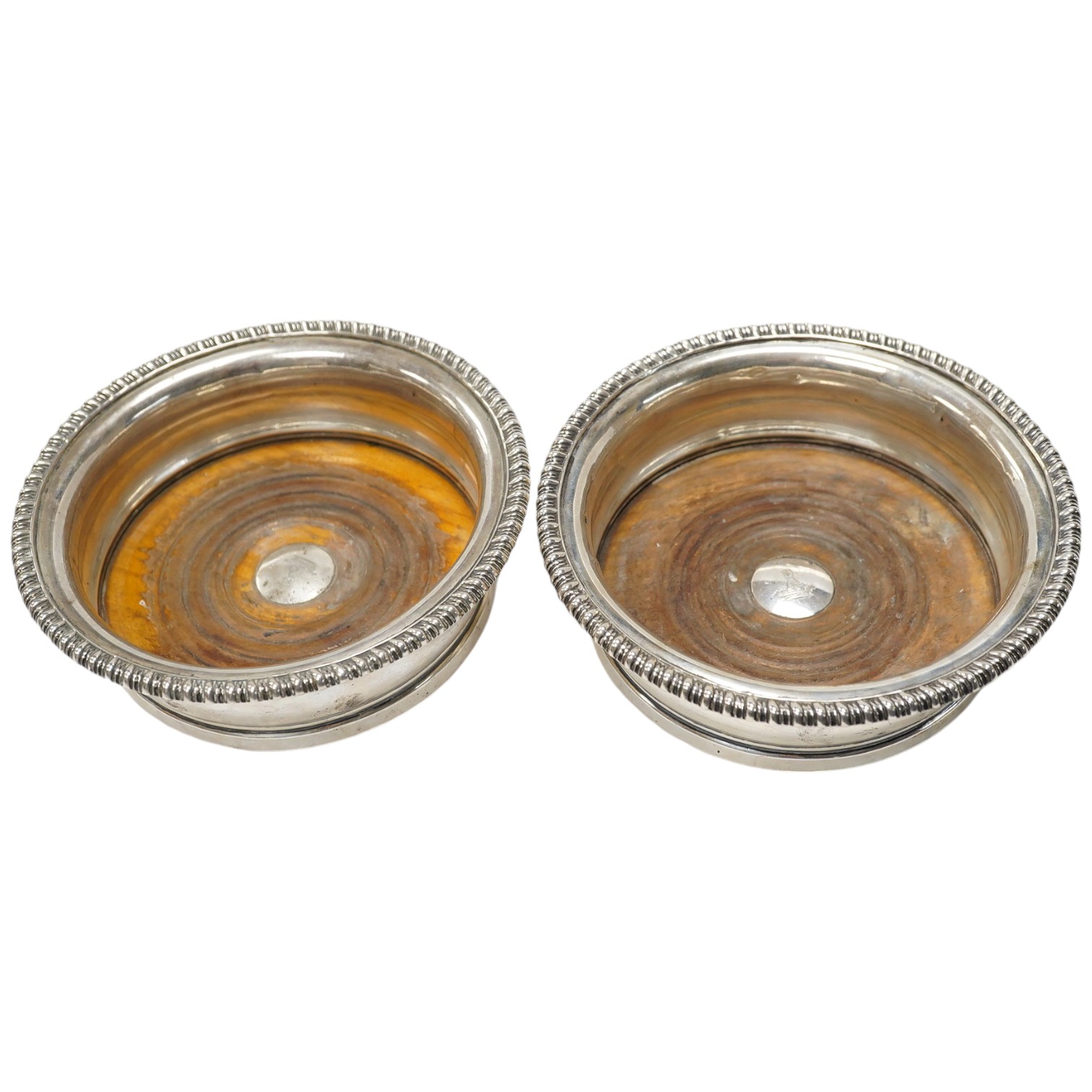 A pair of George III silver wine coasters, by Thomas & John Settle, with gadrooned borders and turned wooden bases, Sheffield, 1821, diameter 15.7cm. Condition - poor to fair